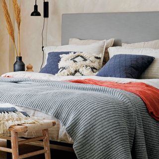 A bed with cream, navy blue, and orange bedding