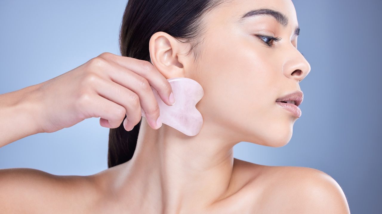 woman using a rose quartz gua sha