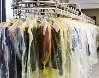 Clothes are wrapped in plastic on a rotating rail at a dry cleaners.