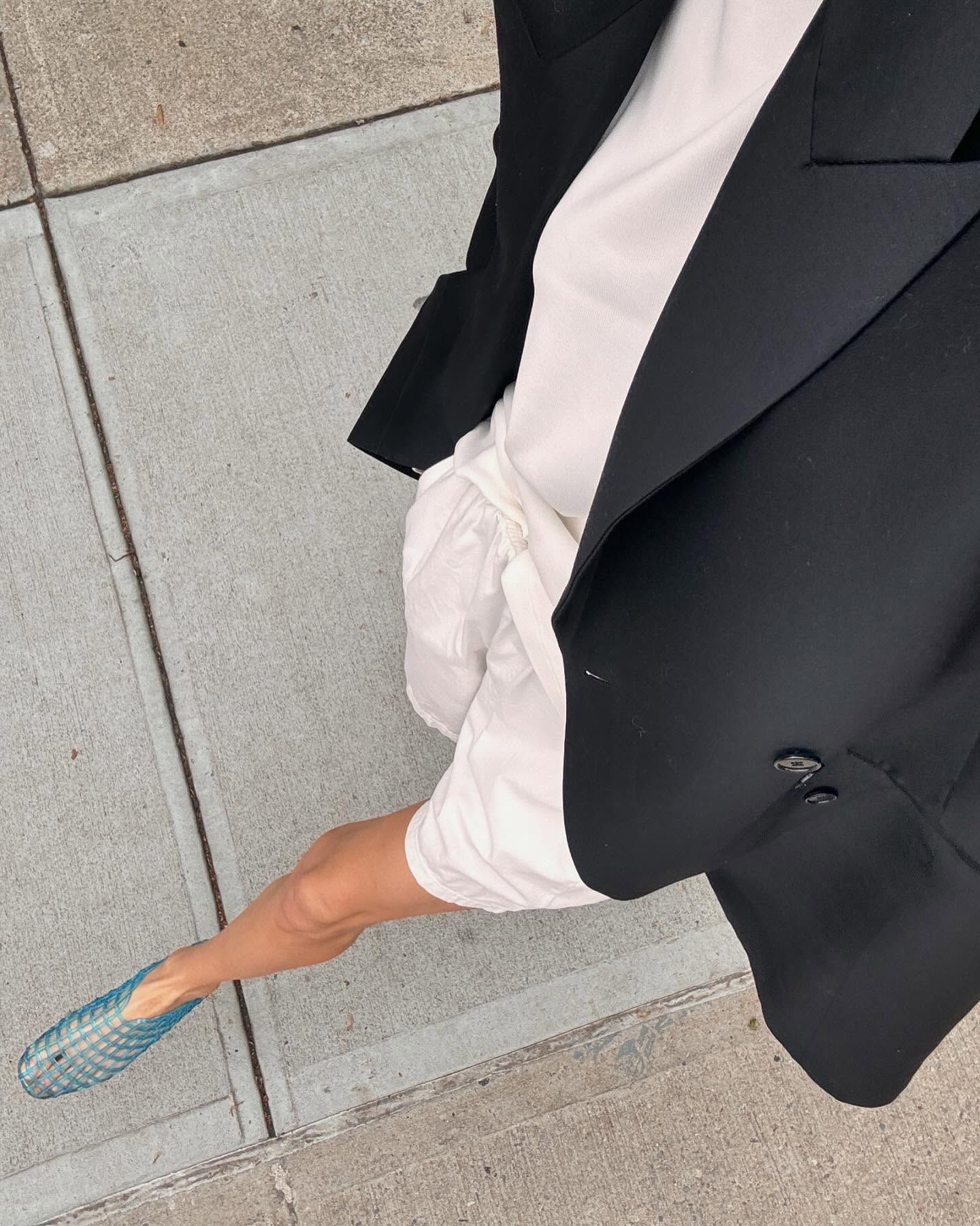 Influencer Courtney Grow walking in NYC wearing an oversize blazer, white tee, white cotton shorts, and The Row blue jelly flats