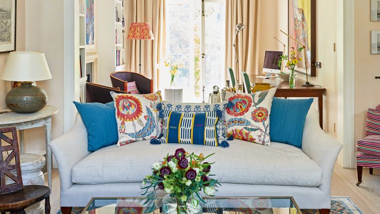 neutral living room with white sofas and colorful, patterned cushions and patterned rug