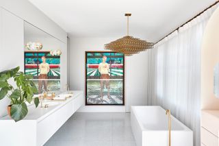 white bathroom with polished brass fixtures and large painting