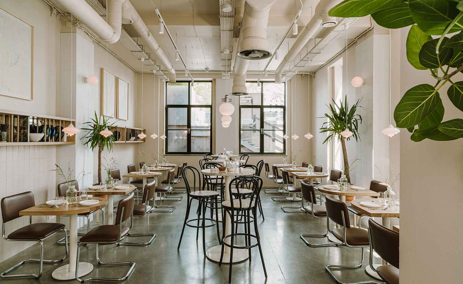 Dining area in neutral, earthy tones. Exposed ceiling showing pipework