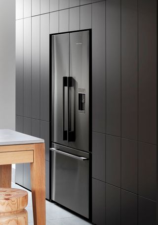 A dark silver fridge with kitchen units built around it