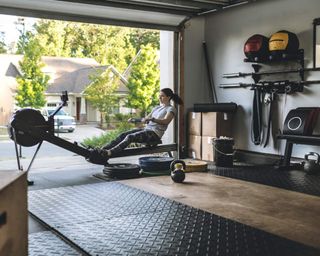 A woman working out in home gym in garage with door open looking out onto front yard