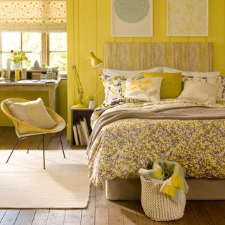 Yellow bedroom with wall panelling, wooden floor and floral bedding