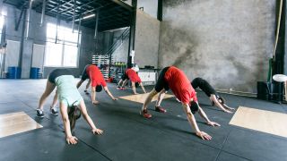 Group of people perform downward dog stretch in the gym to improve shoulder mobility
