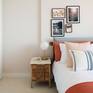 Neutral painted bedroom, bed with grey headboard, cushion, side table