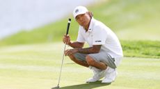 Anthony Kim crouches on the green at JCB Golf and Country Club at LIV Golf UK