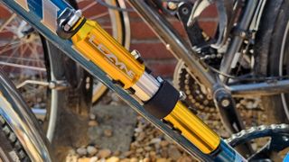 The Lezyne Pressure Drive in anodised gold mounted to a bike frame, seen from the side