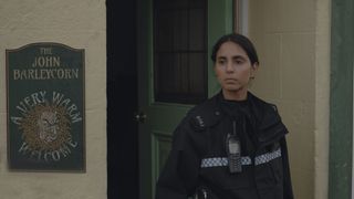 Anjli Mohindra in police uniform as Grace stands outside The John Barleycorn pub in The Red King.