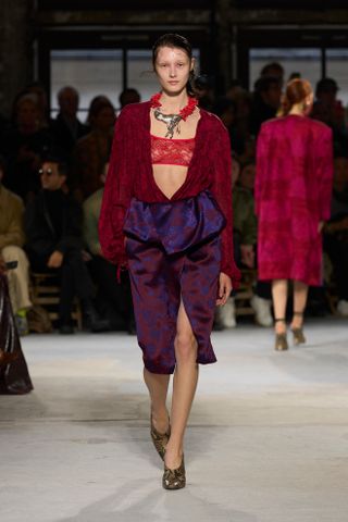 Model walking on the Van Noten runway wearing a lace top and bra.