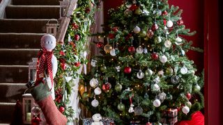 Hallway with large Christmas tree beside the stairs decorated in red and white