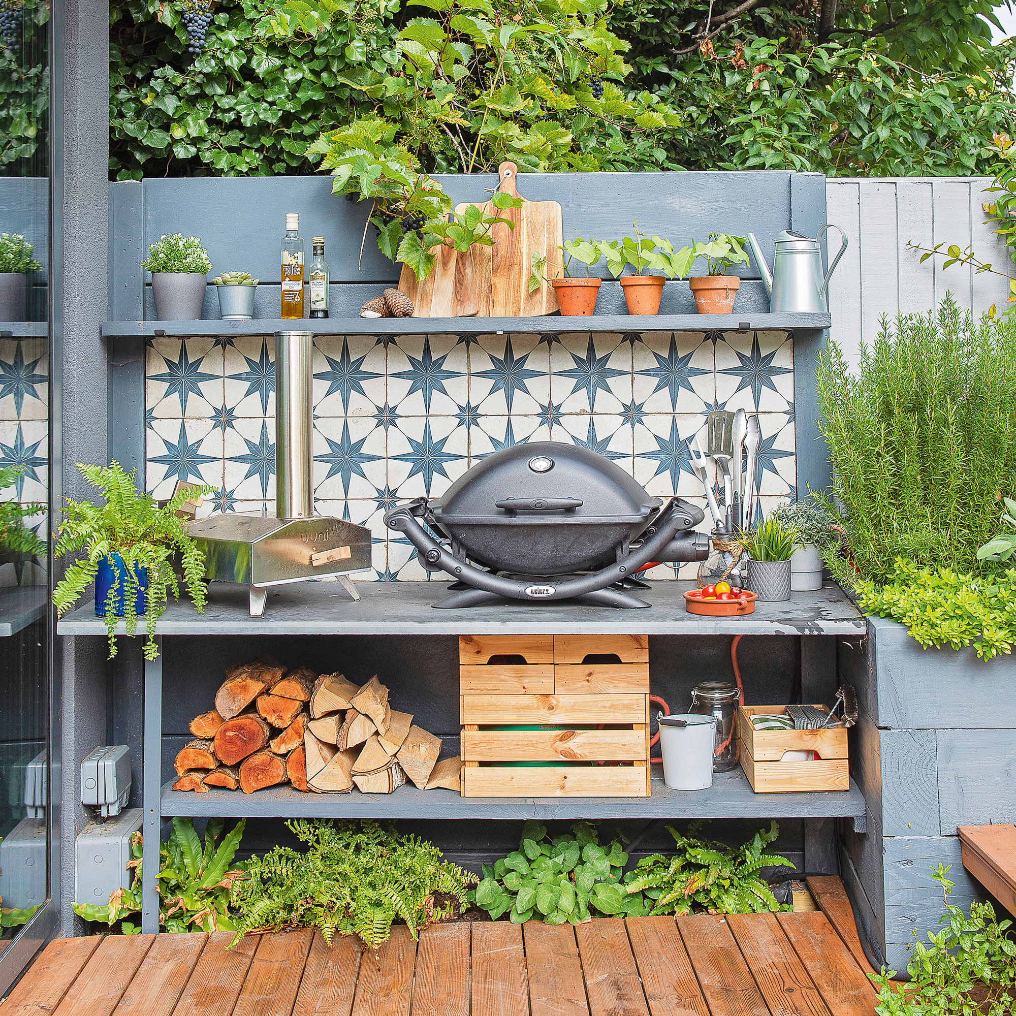 an outdoor kitchen on a patio with a bold tiled splashback and a Weber portable barbecue