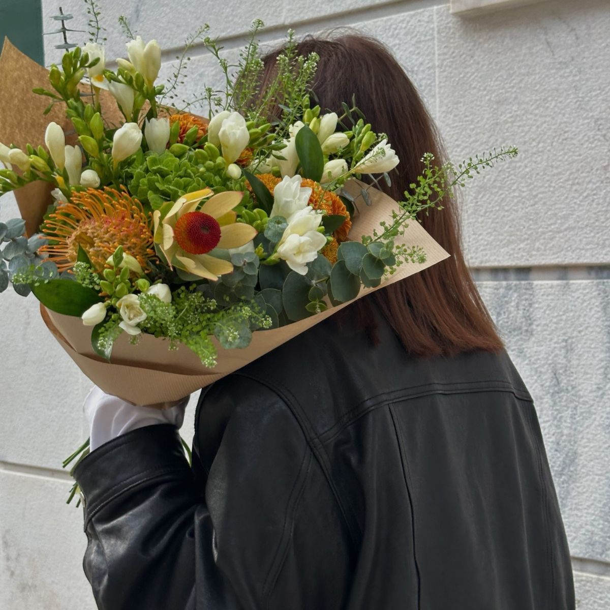 A woman carrying a colourful bouquet of flowers