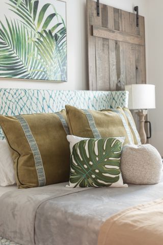 bedroom with green accents, tropical cushions and artwork rustic door, green linear headboard, gray and stone bedding