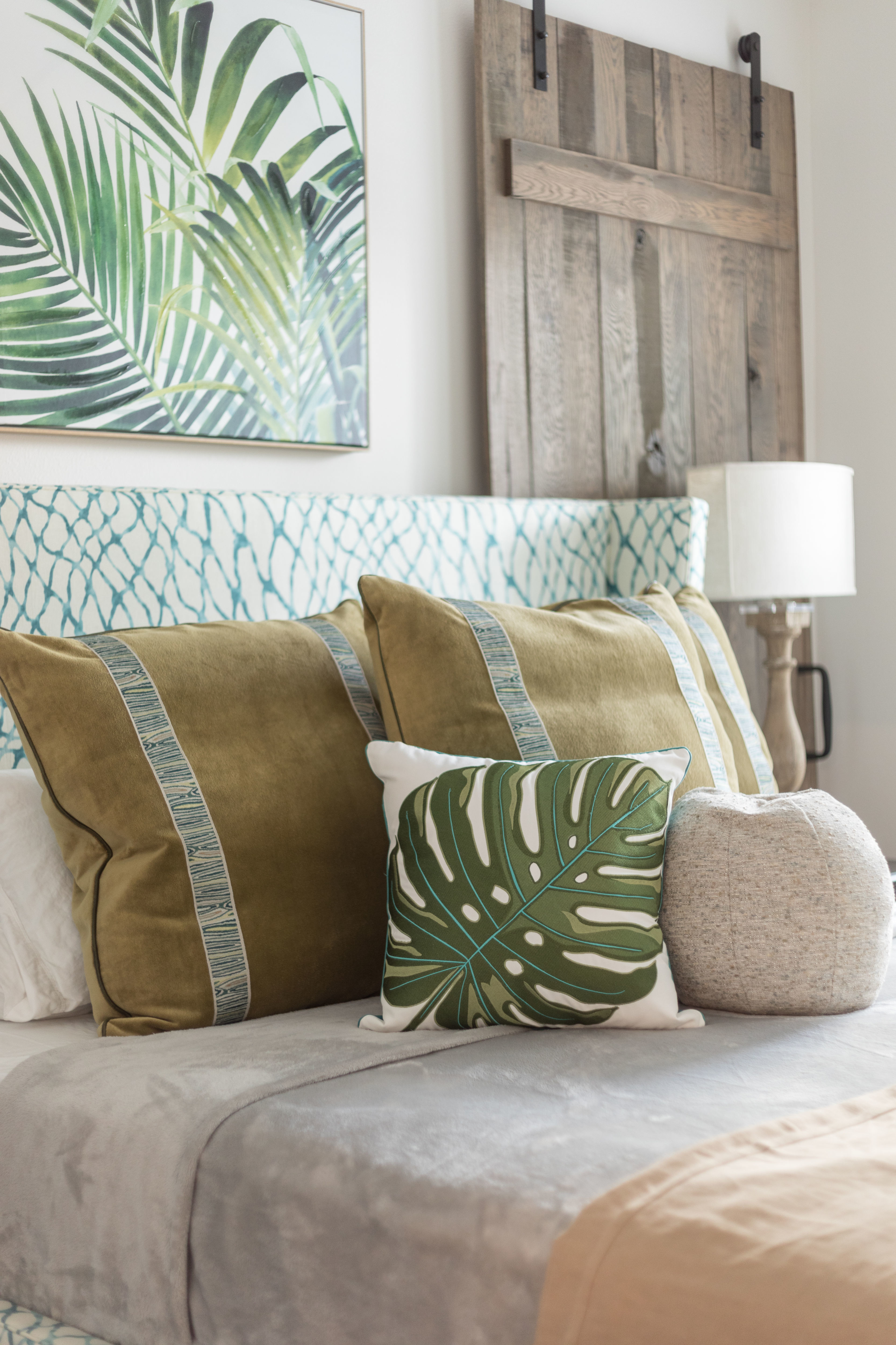 bedroom with green accents, tropical cushions and artwork rustic door, green linear headboard, gray and stone bedding