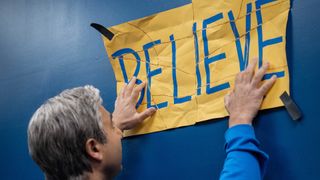 Nathan Shelley hangs up the Believe sign in Ted Lasso