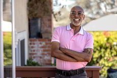 Portrait of an African-American mature man with his arms crossed, looking at the camera on his outdoor deck.