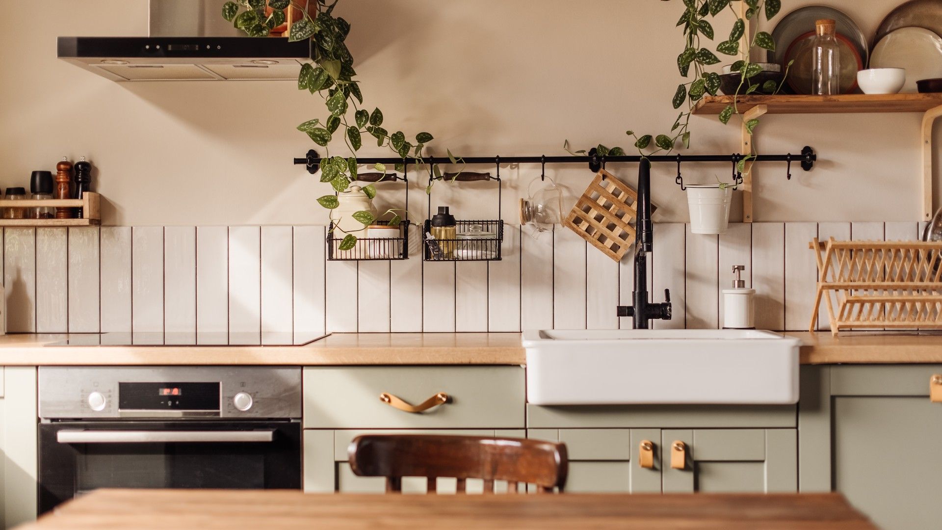 a modern country kitchen, with floating shelves, butler's sink, green cabinets and a wooden island