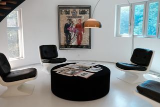 poster on wall behind retro chairs, round table and pendant lamp