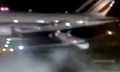 A smaller plane passes under a jumbo jet on a JFK runway, a "fender bender" that left the little plane spun around. 