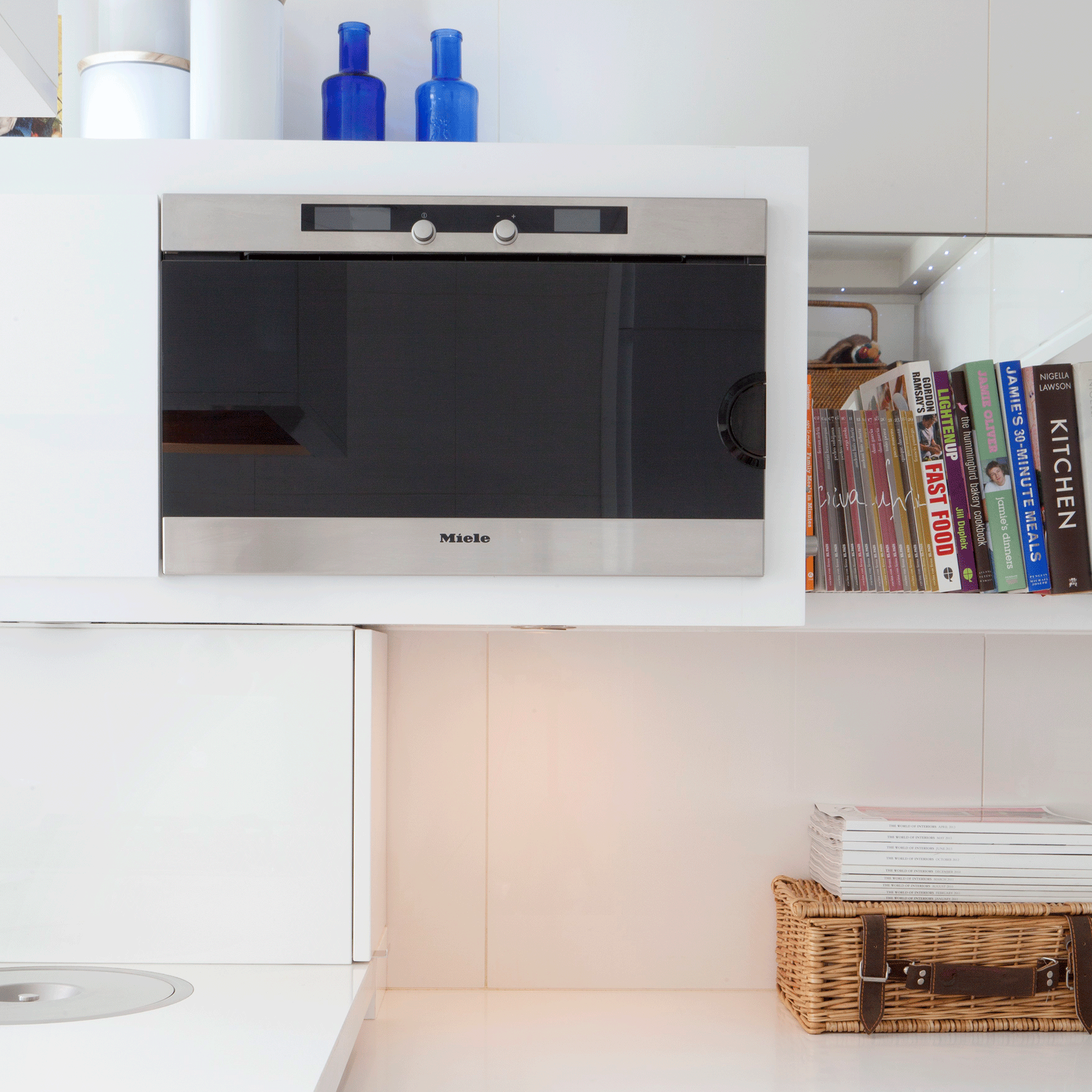 Silver microwave in white kitchen with book shelf