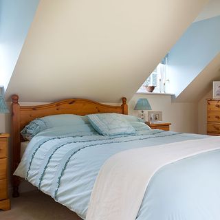 bedroom with blue and white wall wooden bed with blue cushion