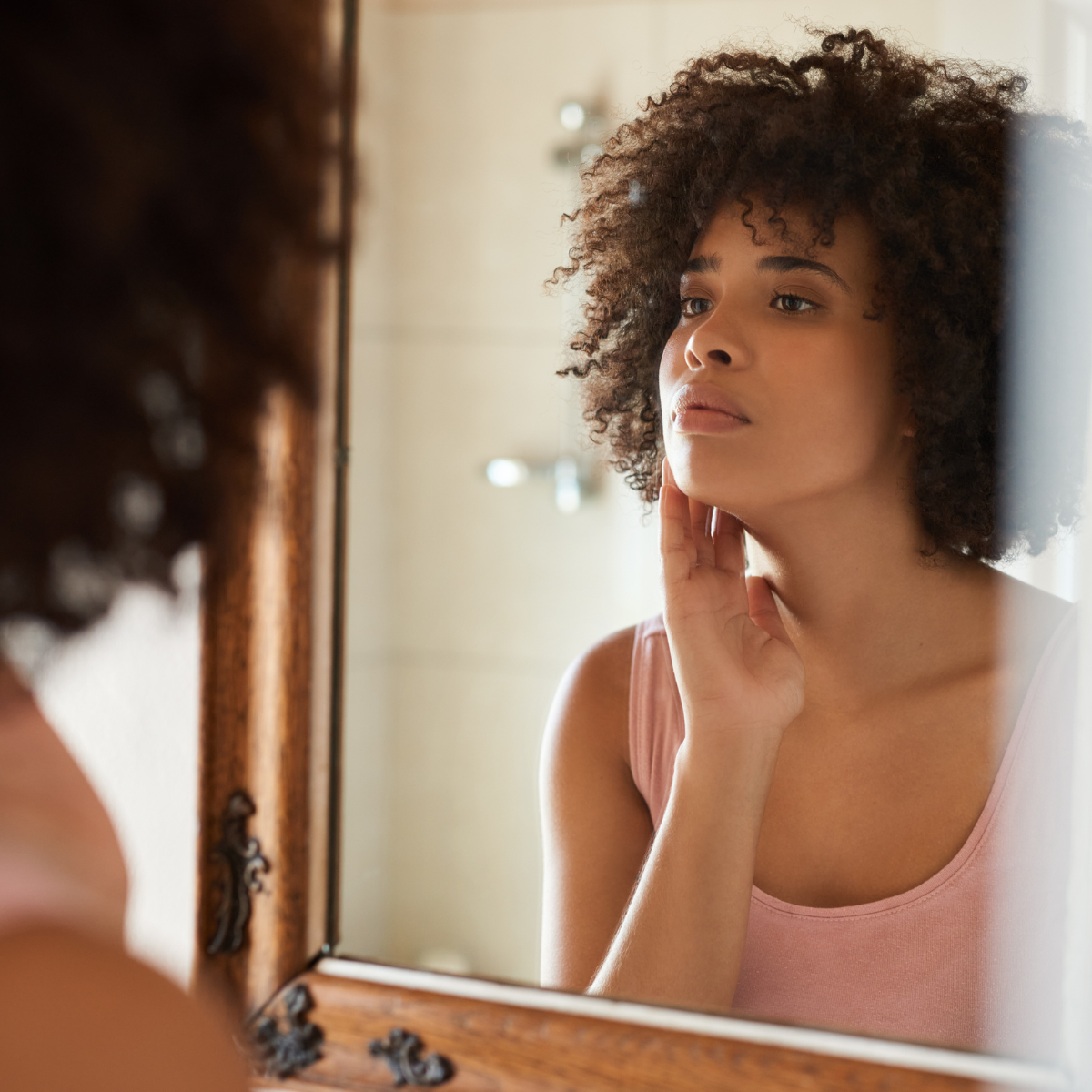 Beef tallow skincare -woman examining her skin in a bathroom mirror