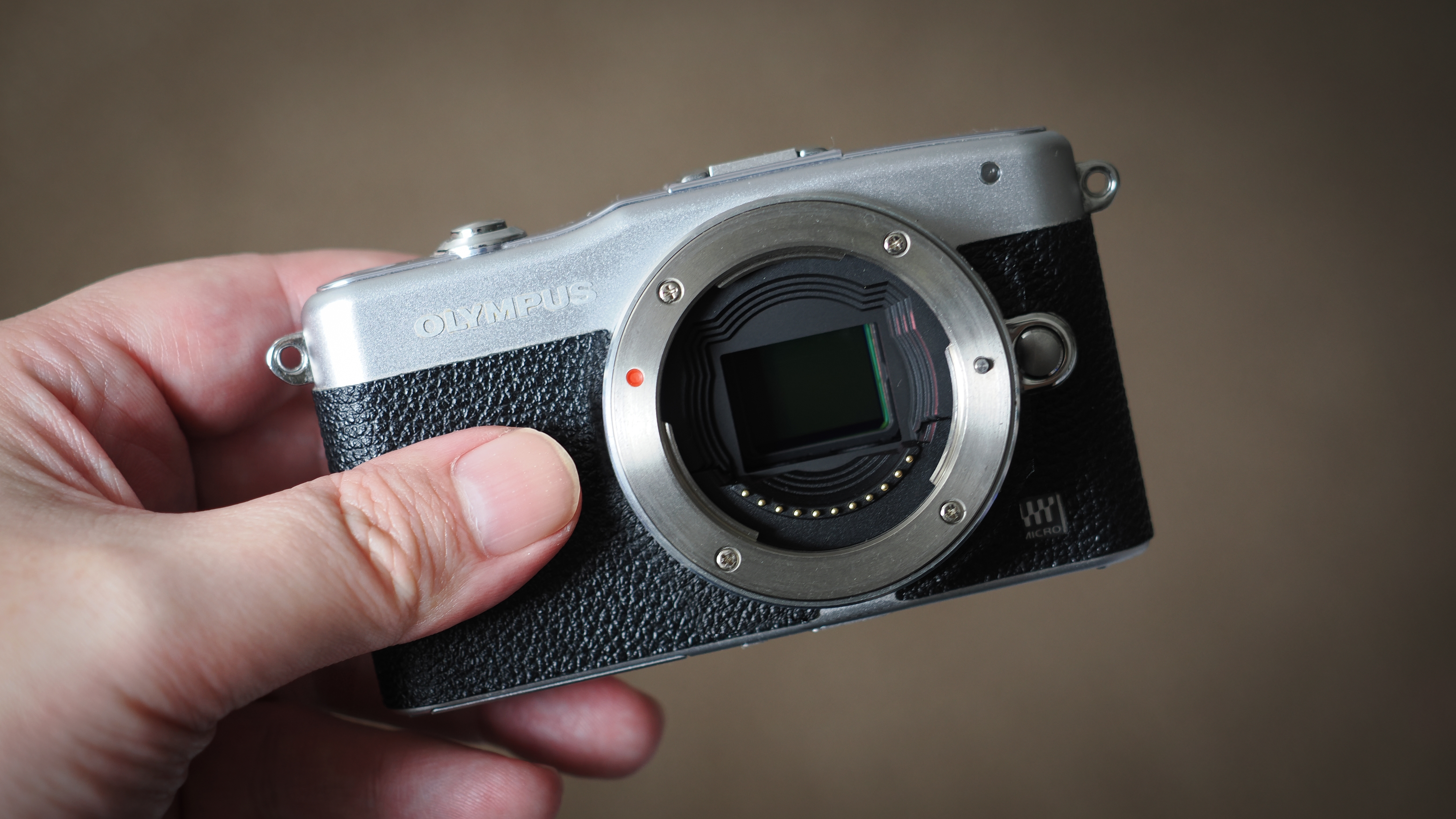 Olympus PEN E-PM1 camera being held in hand