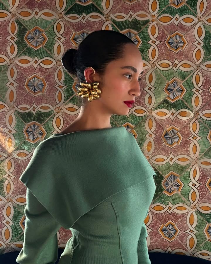 A woman wearing red lipstick with her hair slicked back and statement earrings.