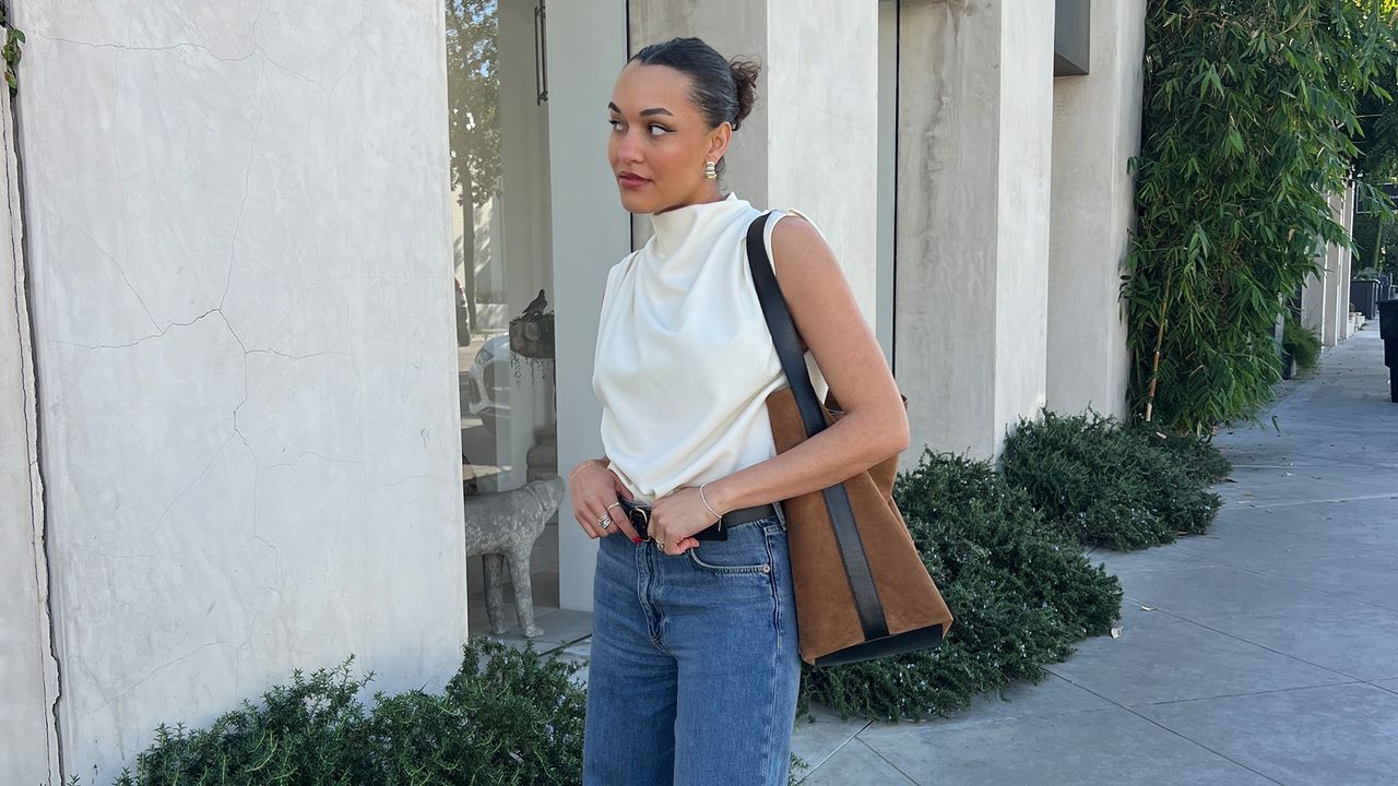 anneliese henderson wearing jeans and a white top and a suede bag