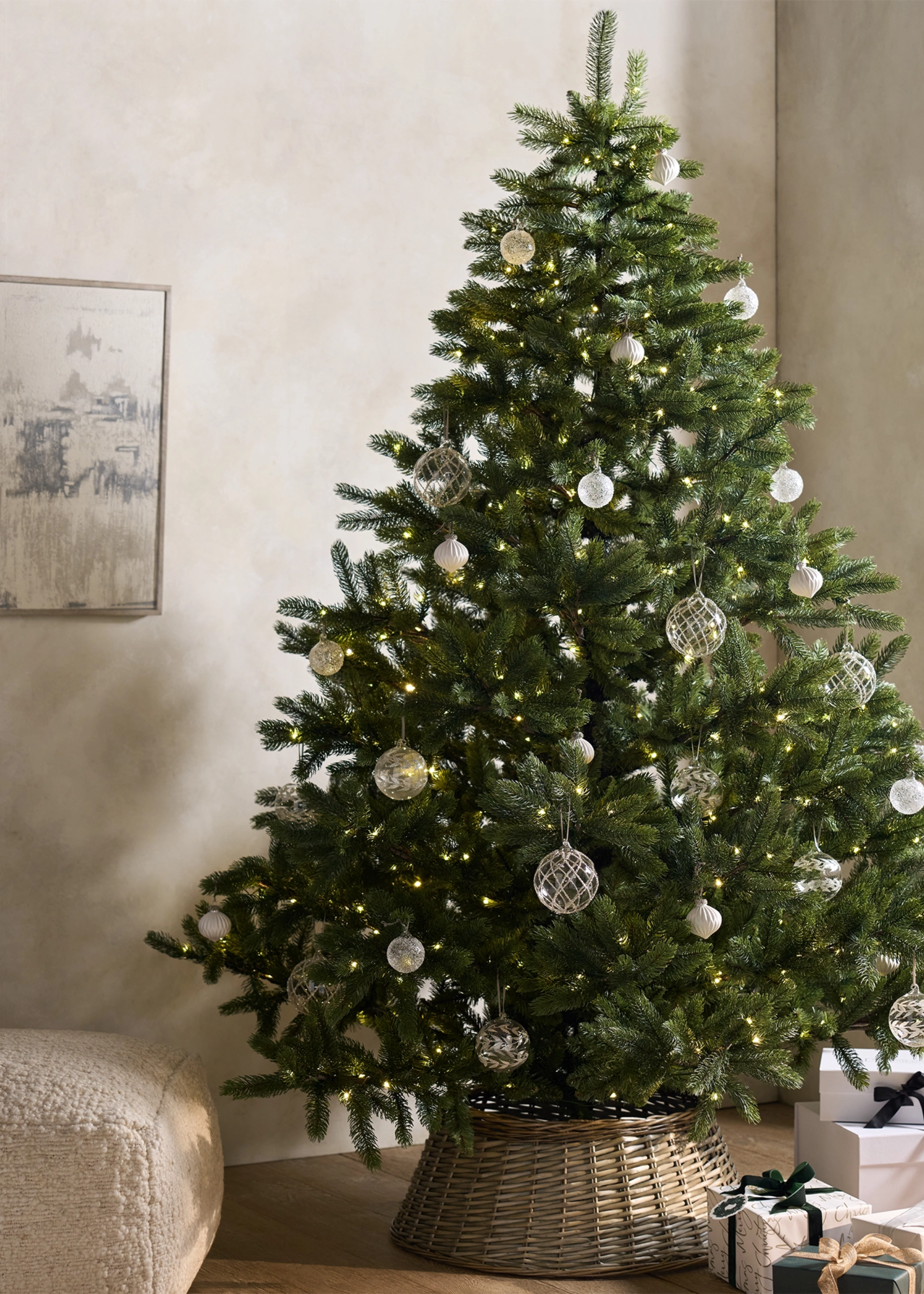 A Christmas tree with glass baubles, a rattan skirt, and a scattering of presents