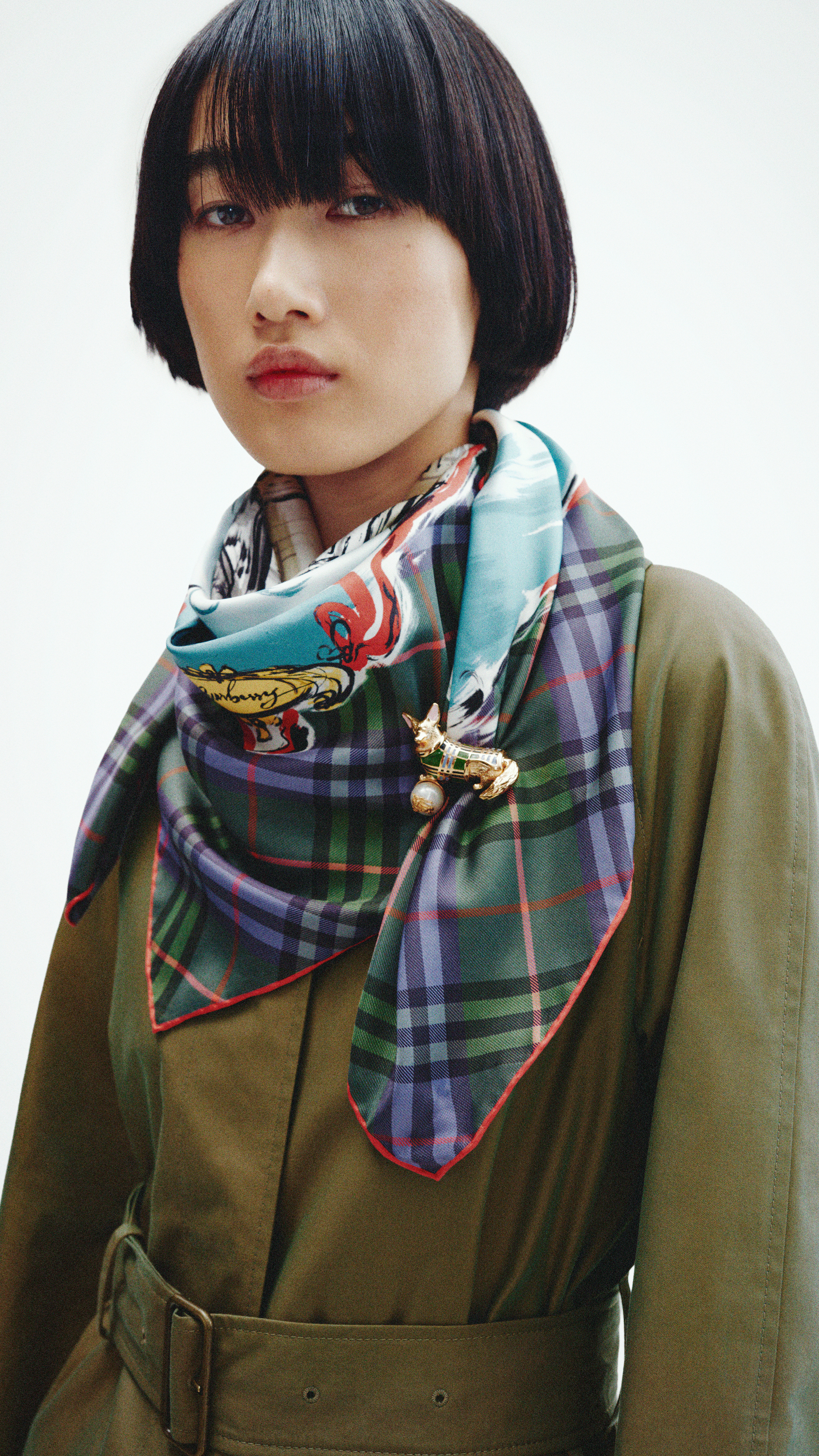 A model wearing a Burberry tartan scarf and green coat