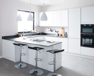 white handless kitchen with white pendant lights