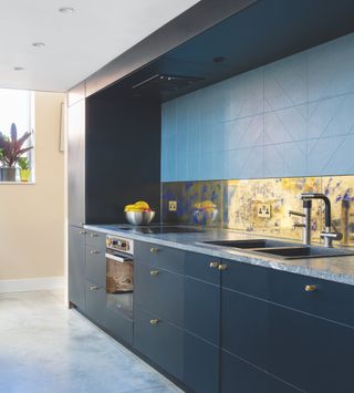 blue kitchen with sink and tap and metallic splashback