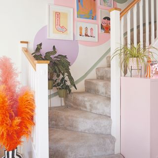 A staircase with a greige soft carpet, a gallery wall and a feature painted on the wall