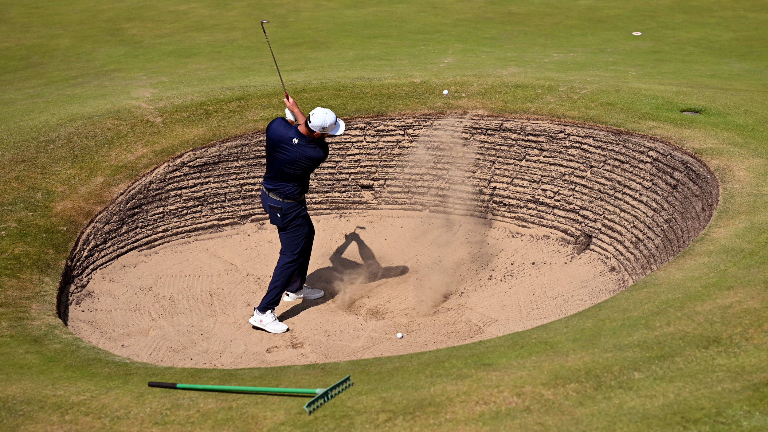 Jon Rahm plays out of a revetted bunker at Royal Birkdale during a practice round in 2026