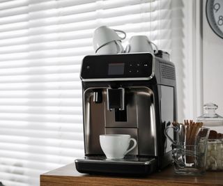 An automatic coffee maker in front of a white wall
