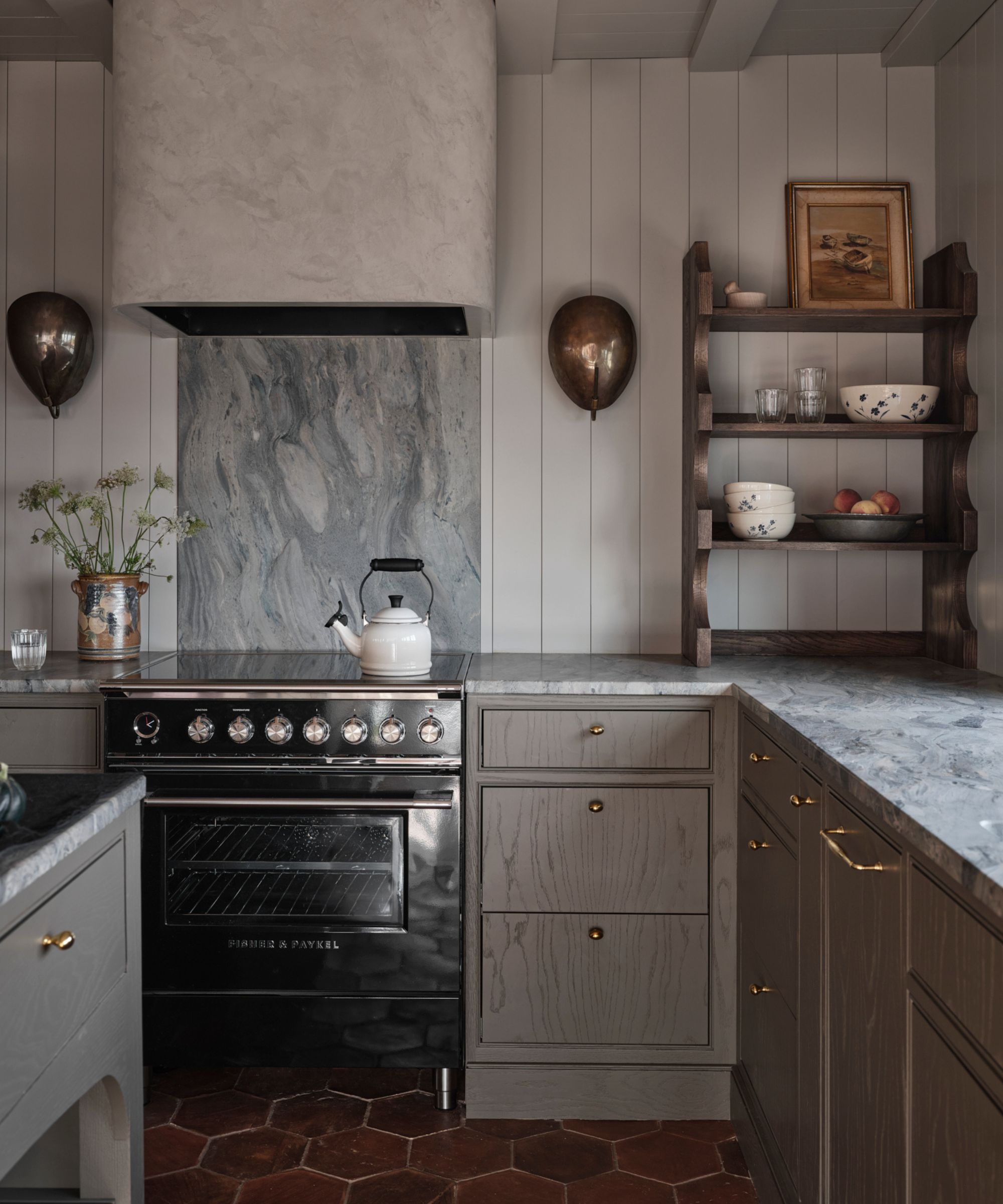 an earthy brown grey small kitchen with blue veined marble countertops and terracotta floor tiles