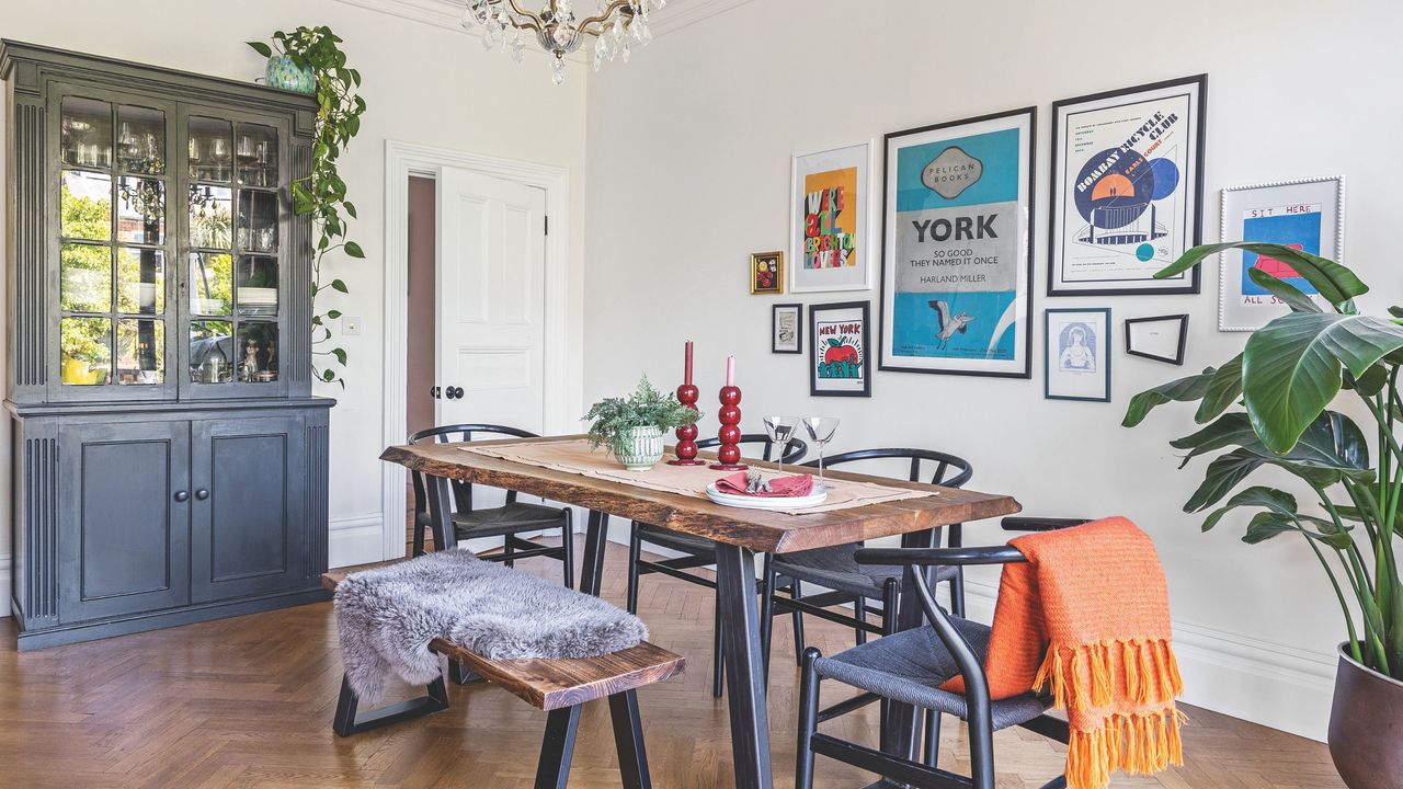 White painted dining room with a gallery wall, wooden floor, a wooden dining room table, and a blue painted drinks cabinet in it