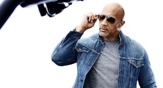 Dwayne Johnson in sunglasses and a denim jacket.