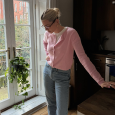 Influencer @lindseyholland_ wears a pink cardigan with blue jeans over a white t-shirt.