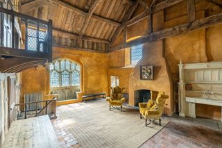 A large orange room with timber beams in a pitched ceiling and stone fireplace