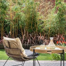 Conversation set with table and chair, overlooking a screen of bamboo plants