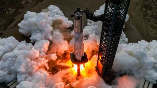 aerial view of a large silver rocket firing its engines on a launch mount