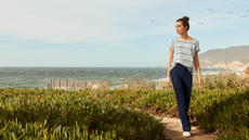 A woman walking along a grassy beach scene wearing clothes from Lands' End