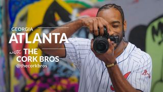 Michelangelo Corkrum taking a photo in front of a wall of graffiti next to the text “Georgia Atlanta with the Cork Bros”