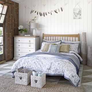 white bedroom with white wall panelling and soft blue accents