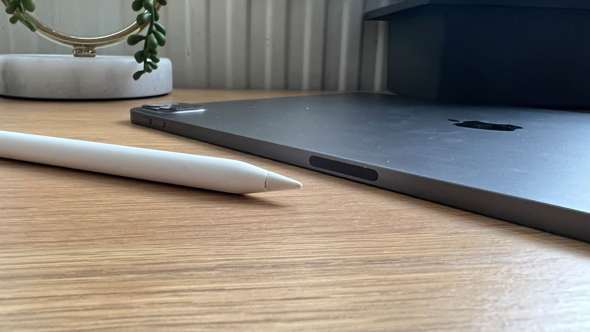 A closeup of the Apple Pencil on a table next to the 12.9in Apple iPad Pro
